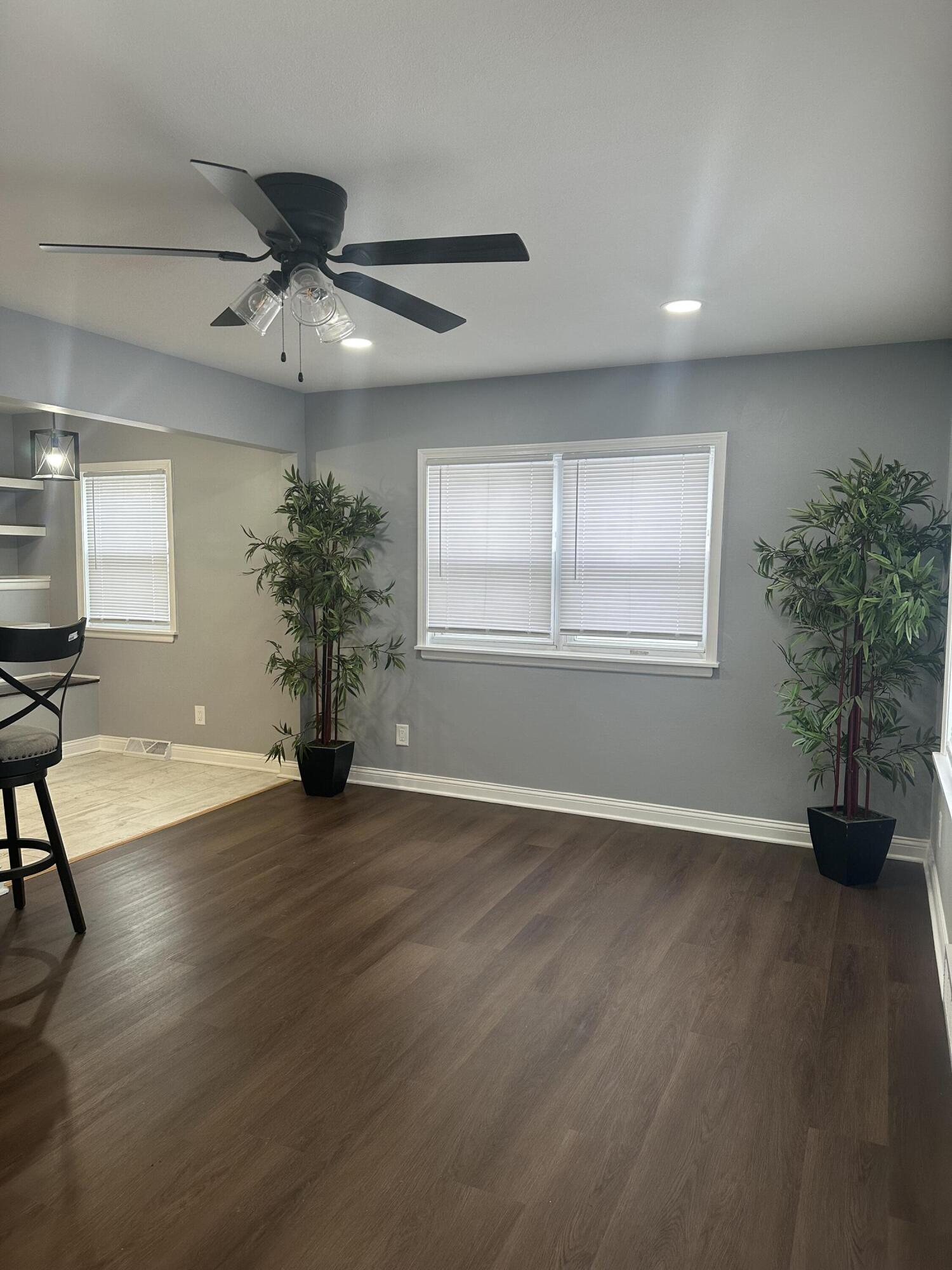 556 Gerry Street Gary, IN 46406 - Photo 2 of 21 an empty room with wooden floor chandelier fan and windows