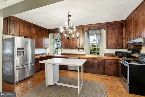 a kitchen with stainless steel appliances granite countertop a refrigerator a sink dishwasher a stove and white countertops with cabinets