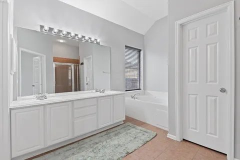 a spacious bathroom with a double vanity sink a mirror and a bathtub