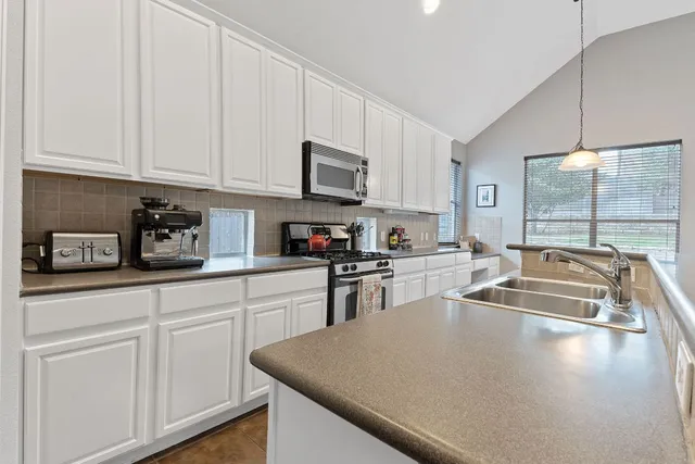 a kitchen with stainless steel appliances granite countertop a sink a stove and white cabinets