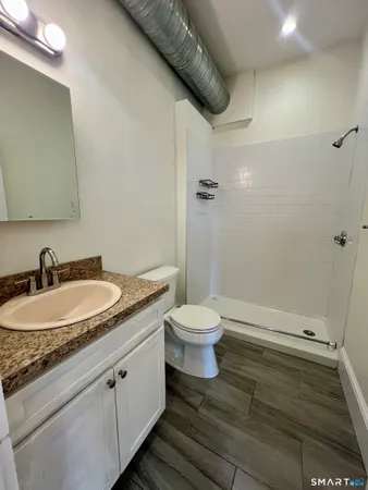 a bathroom with a granite countertop sink toilet and shower