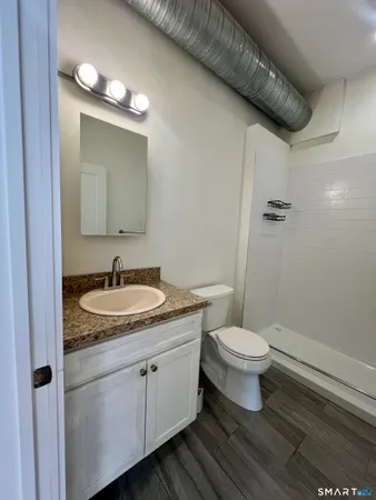 a bathroom with a granite countertop sink a toilet and a mirror