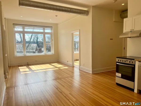 a view of empty room with wooden floor and fan