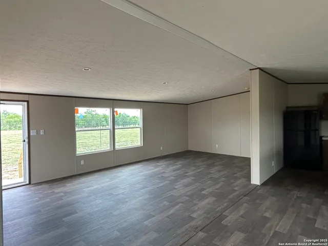 a view of kitchen and empty room with wooden floor