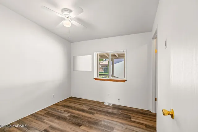 a view of a bedroom with wooden floor and a ceiling fan