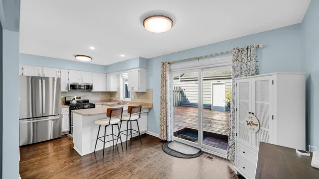 a kitchen with stainless steel appliances granite countertop a refrigerator a stove a sink and white cabinets