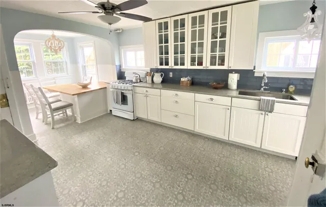 a large white kitchen with cabinets a sink a window and a potted plant