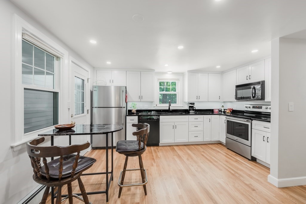 21 Cutler Drive Ashland, MA 01721 - Photo 4 of 28 a kitchen with stainless steel appliances kitchen island granite countertop a refrigerator a stove a sink dishwasher and white cabinets with wooden floor
