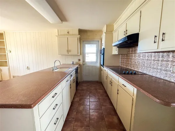 a large kitchen with granite countertop a sink and dishwasher a stove top oven with wooden floor