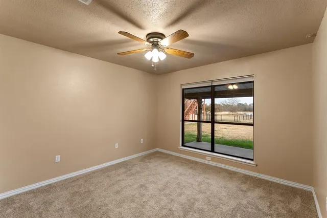 an empty room with windows and ceiling fan