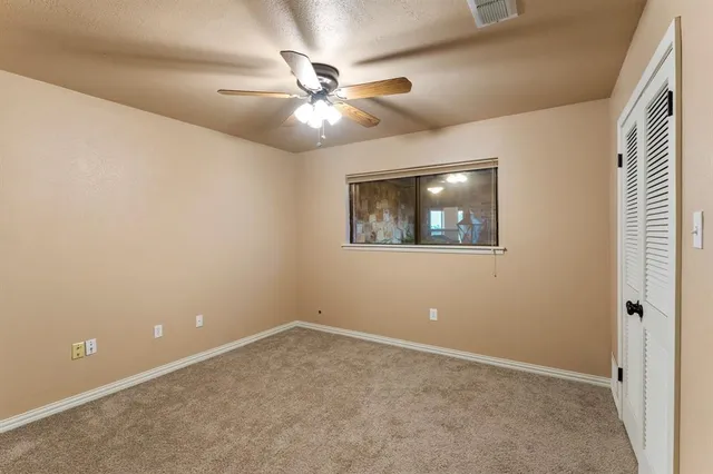 an empty room with a window and a fan