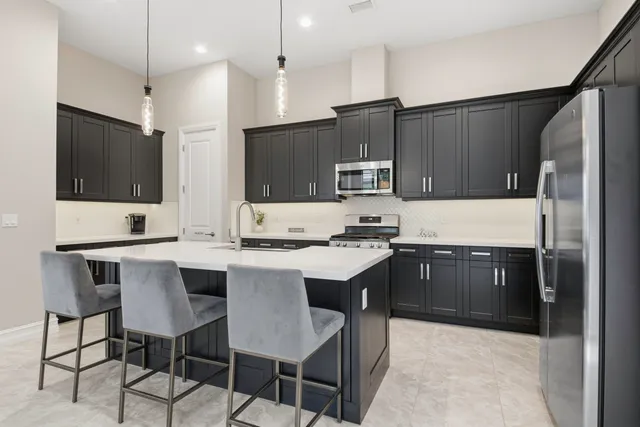 a kitchen with a stove a refrigerator a sink a dining table and chairs with wooden floor