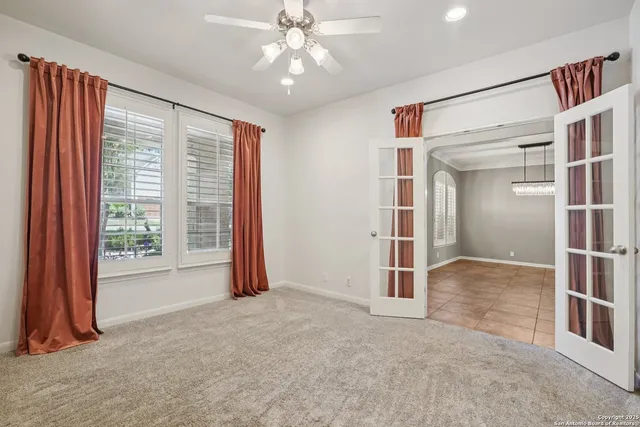 an empty room with wooden floor ceiling fan and windows