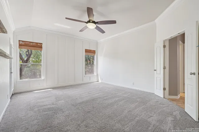 a view of an empty room with chandelier fan and wooden floor