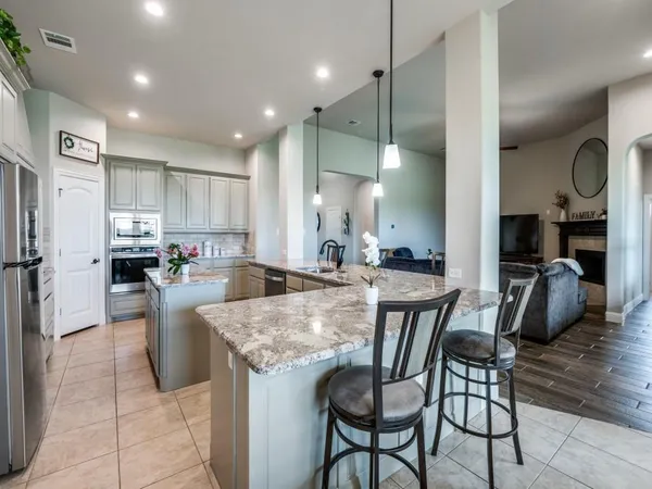 a kitchen with stainless steel appliances granite countertop table chairs sink and cabinets