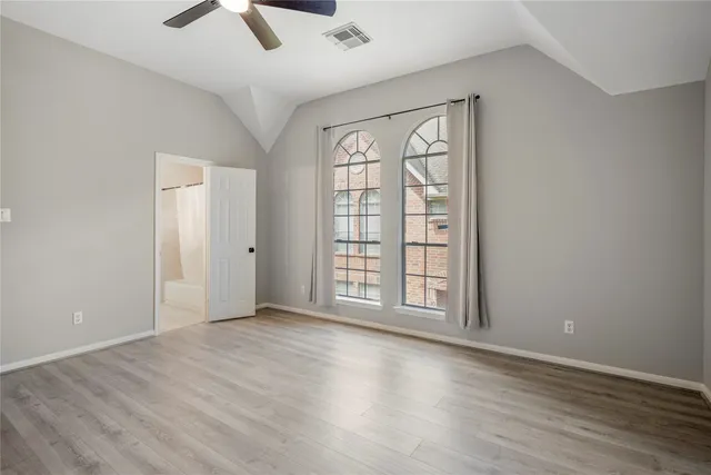 an empty room with windows and ceiling fan