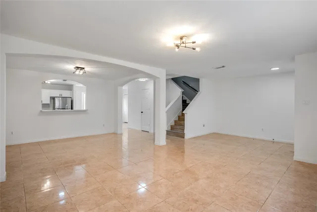 an empty room with chandelier fan and windows