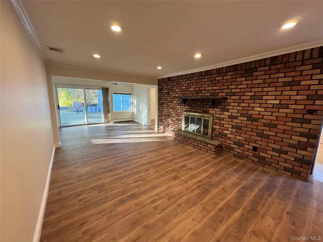 a view of empty room with wooden floor and fireplace