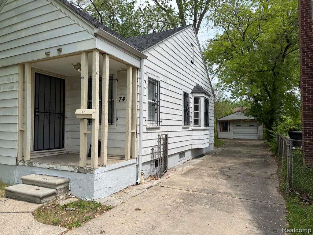 7416 Heyden Detroit, MI 48228 - Photo 2 of 16 View of side of home featuring a detached garage, roof with shingles, an outbuilding, and driveway