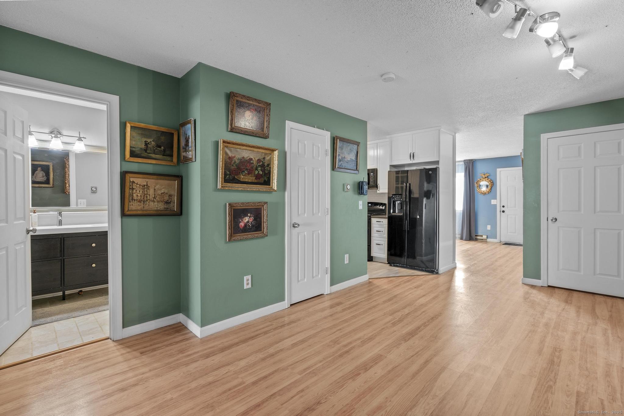 a view of a kitchen with refrigerator and wooden floor