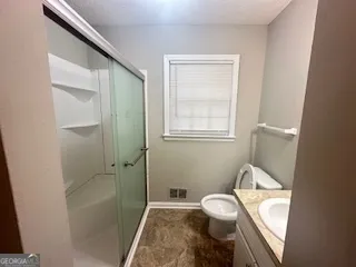 a bathroom with a granite countertop sink a toilet and shower