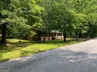 a view of a house with a big yard and large trees