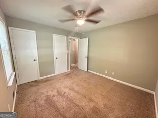 an empty room with closet and a ceiling fan