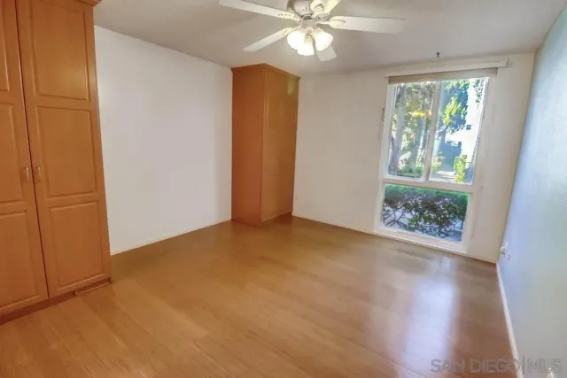an empty room with wooden floor chandelier fan and windows