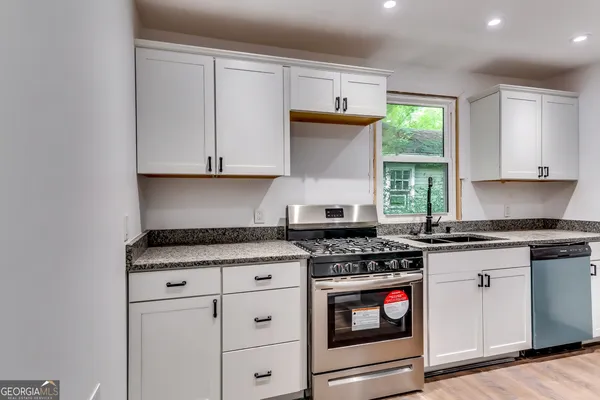 a kitchen with granite countertop a stove sink and cabinets