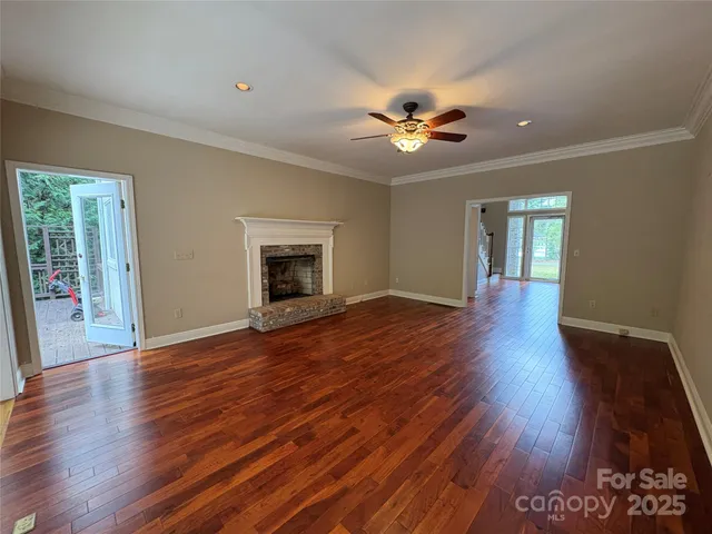 a view of an empty room with wooden floor and a fireplace