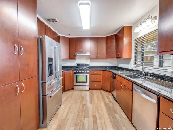 a kitchen with stainless steel appliances granite countertop a refrigerator a sink dishwasher a stove and white countertops with wooden floor