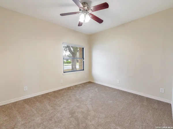 an empty room with windows and fan