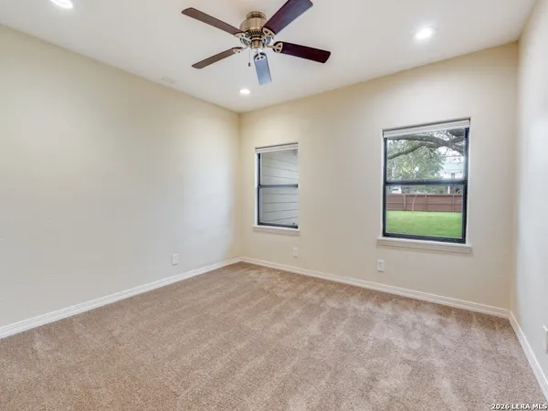 an empty room with windows and fan