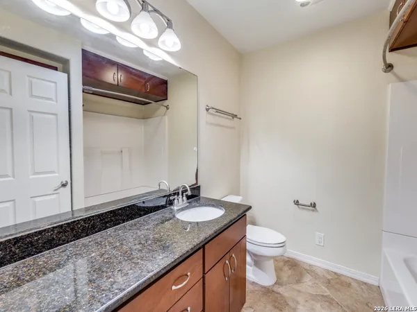 a bathroom with a granite countertop sink toilet and large mirror