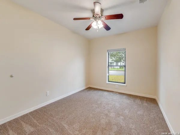 an empty room with chandelier fan and windows
