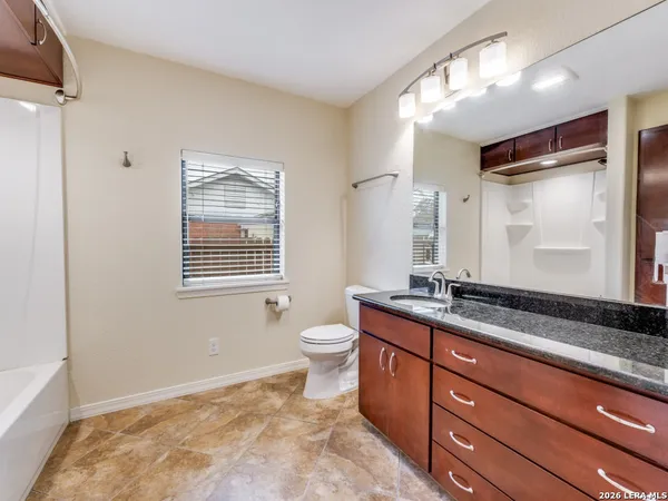 a bathroom with a granite countertop sink toilet and mirror