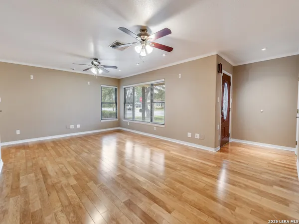 a view of an empty room with wooden floor and a window