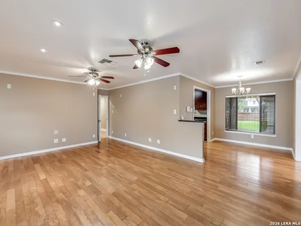 a view of an empty room with a window and wooden floor