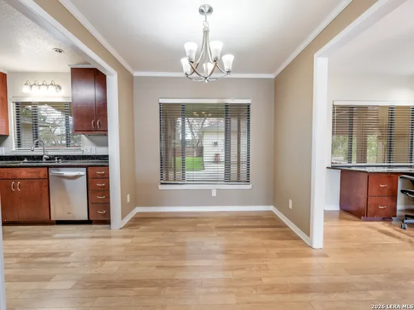 a view of an empty room with kitchen and window