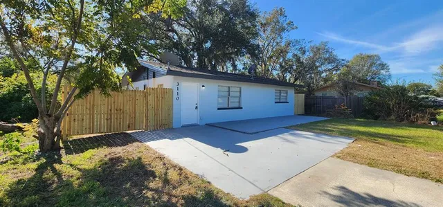 a view of backyard with wooden fence and large trees