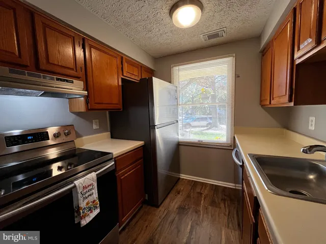 a kitchen that has a sink wooden cabinets and stainless steel appliances
