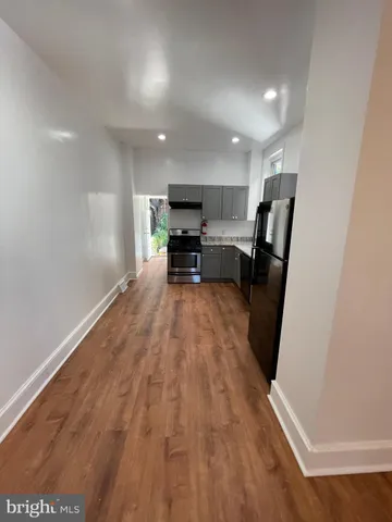 a view of kitchen with stainless steel appliances refrigerator stove microwave and chair