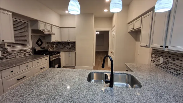 a kitchen with granite countertop a sink stainless steel appliances and cabinets