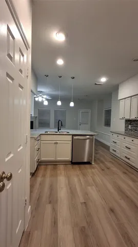 a large white kitchen with a refrigerator a sink dishwasher and a stove with wooden floor