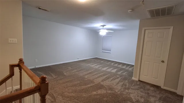 a view of an empty room and chandelier fan