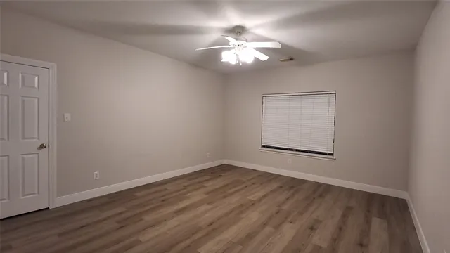 a view of an empty room with wooden floor and a window