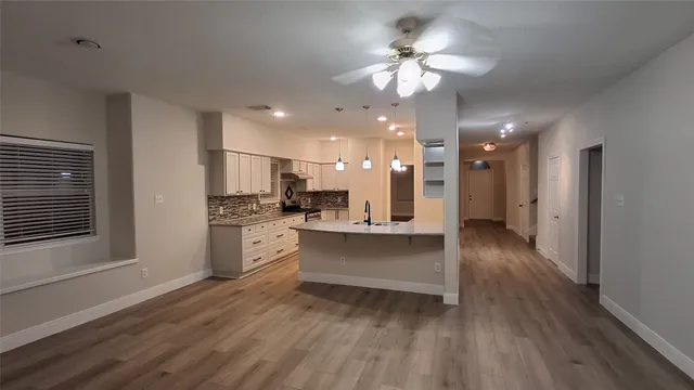 a large white kitchen with a refrigerator a stove a sink dishwasher a oven with white cabinets and wooden floor