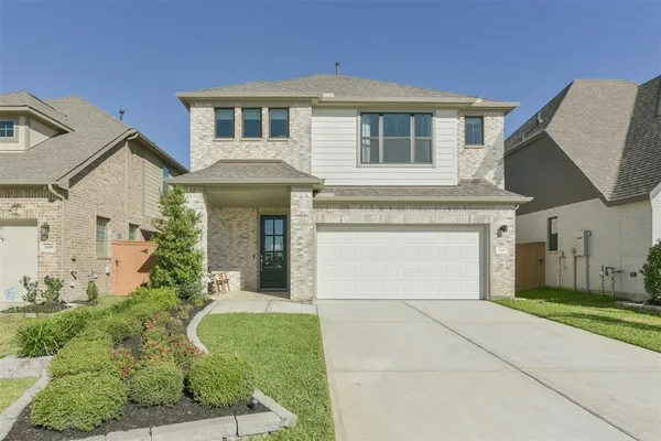 a front view of a house with a garden and garage