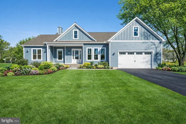 a front view of a house with a garden and trees