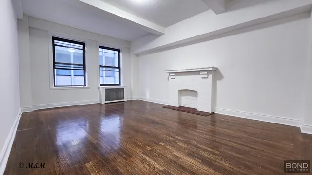 an empty room with wooden floor cabinet and windows